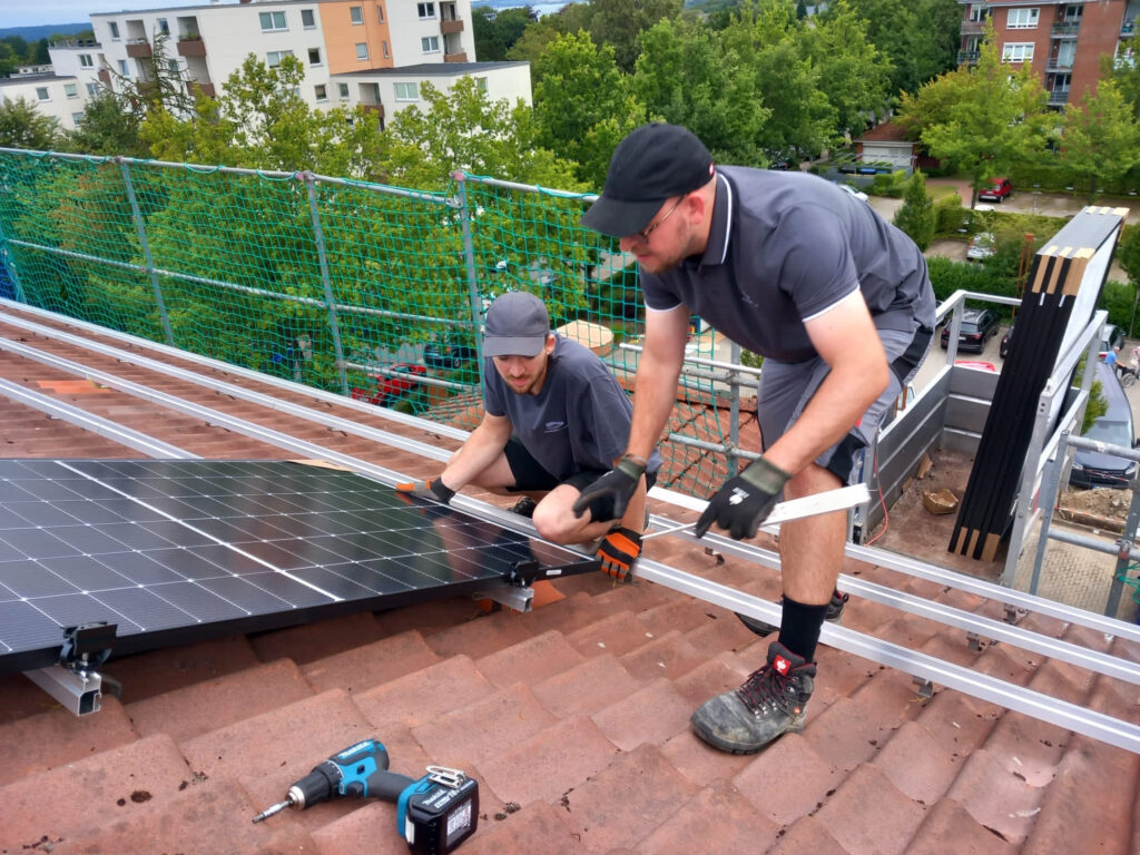 Zwei Handwerker bringen Solarpanels an einem Dach an